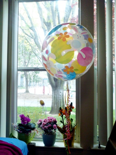 Three flowers on a window sill with a balloon